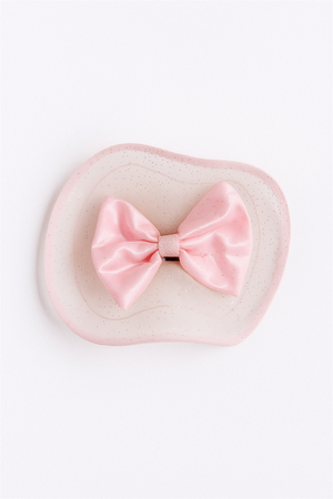 “Pink satin bow hair clip with sheer netting detail, photographed flat against clean white background for clarity.”