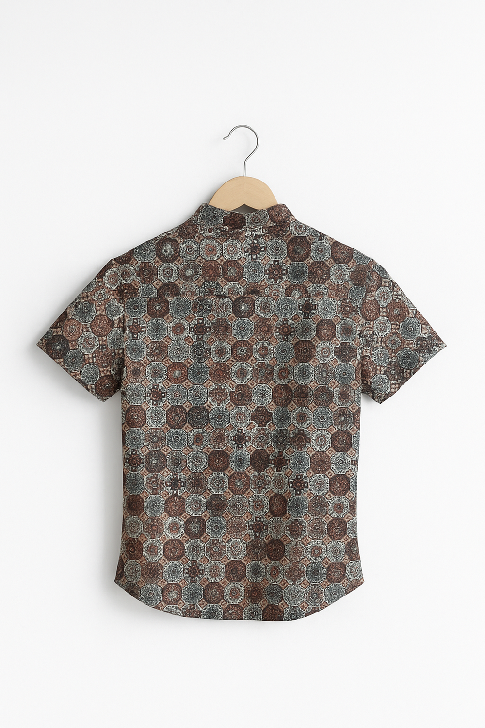 Back view of a boys’ half-sleeve Chinese collar shirt displayed on a wooden hanger against a white background. The shirt features a rich geometric floral print in earthy tones with a straight yoke and neatly stitched hem