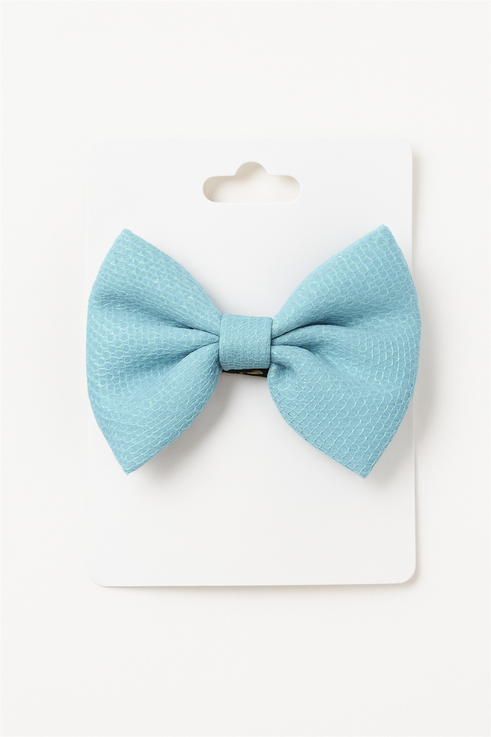 Elegant aqua blue bow hair clip neatly attached to a white display card, showcasing texture and design for retail presentation.