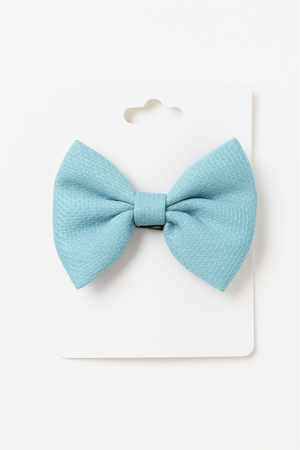 Elegant aqua blue bow hair clip neatly attached to a white display card, showcasing texture and design for retail presentation.