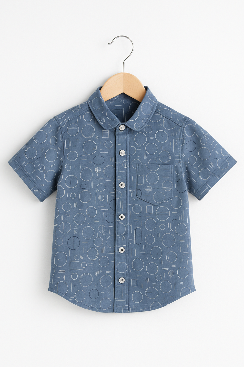 Front view of a boys' half-sleeve club collar shirt displayed on a wooden hanger. The shirt features playful geometric circle patterns and a front chest pocket, perfect for casual wear.
