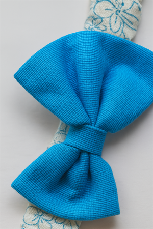 Close-up of textured bright blue fabric bow on patterned elastic hair band, showcasing fine detail, weave, and vibrant craftsmanship.