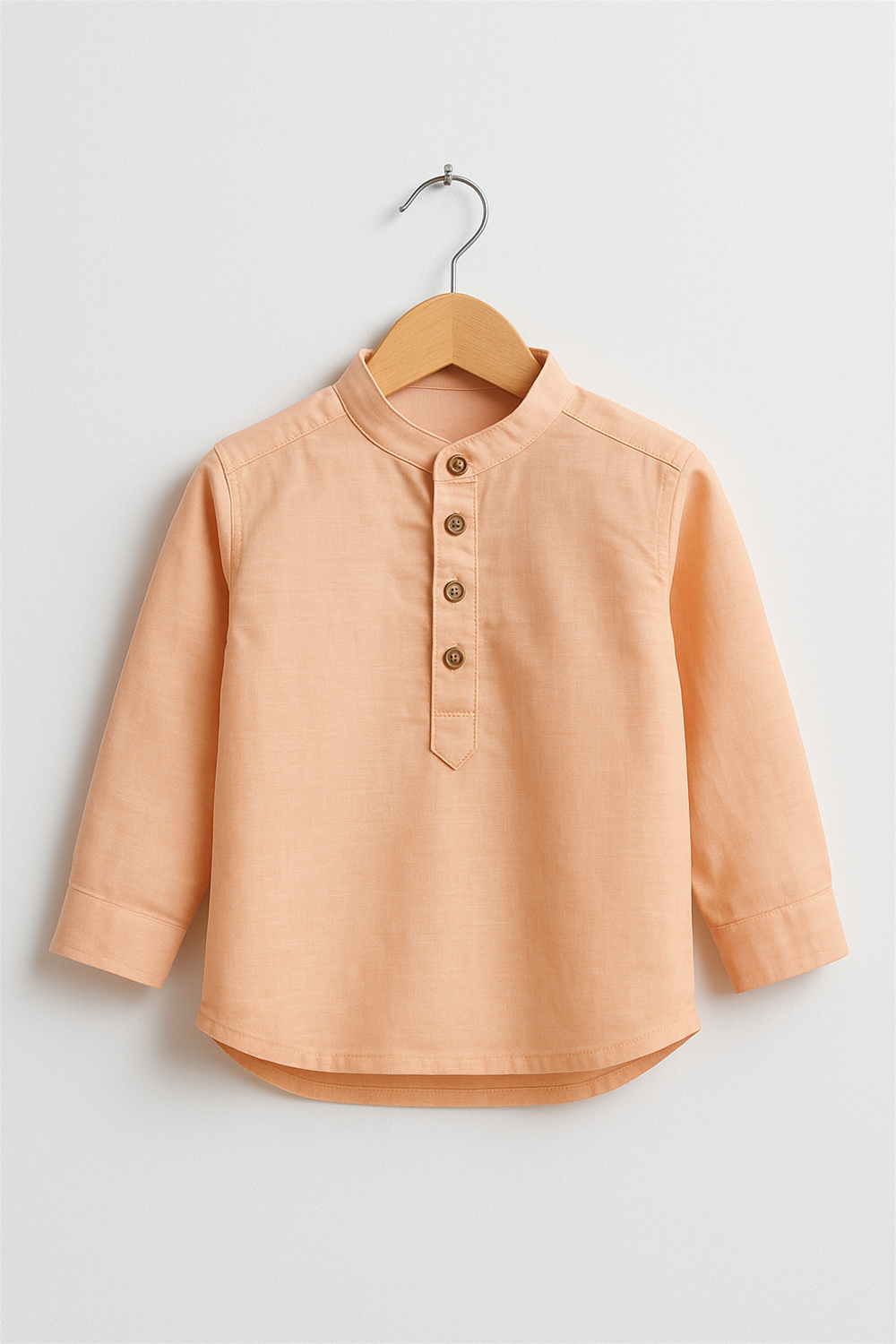 Peach long-sleeve kurta with wooden buttons, displayed on a wooden hanger against a plain white background, showcasing festive attire. 