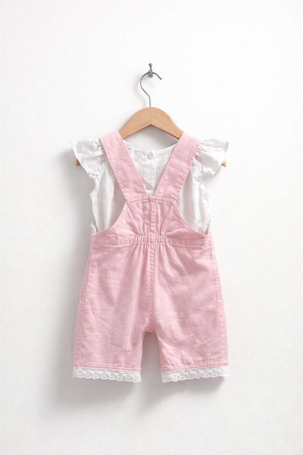 Pink baby dungaree with white inner top, elasticated back waist, lace-trim hem, neatly displayed on wooden hanger