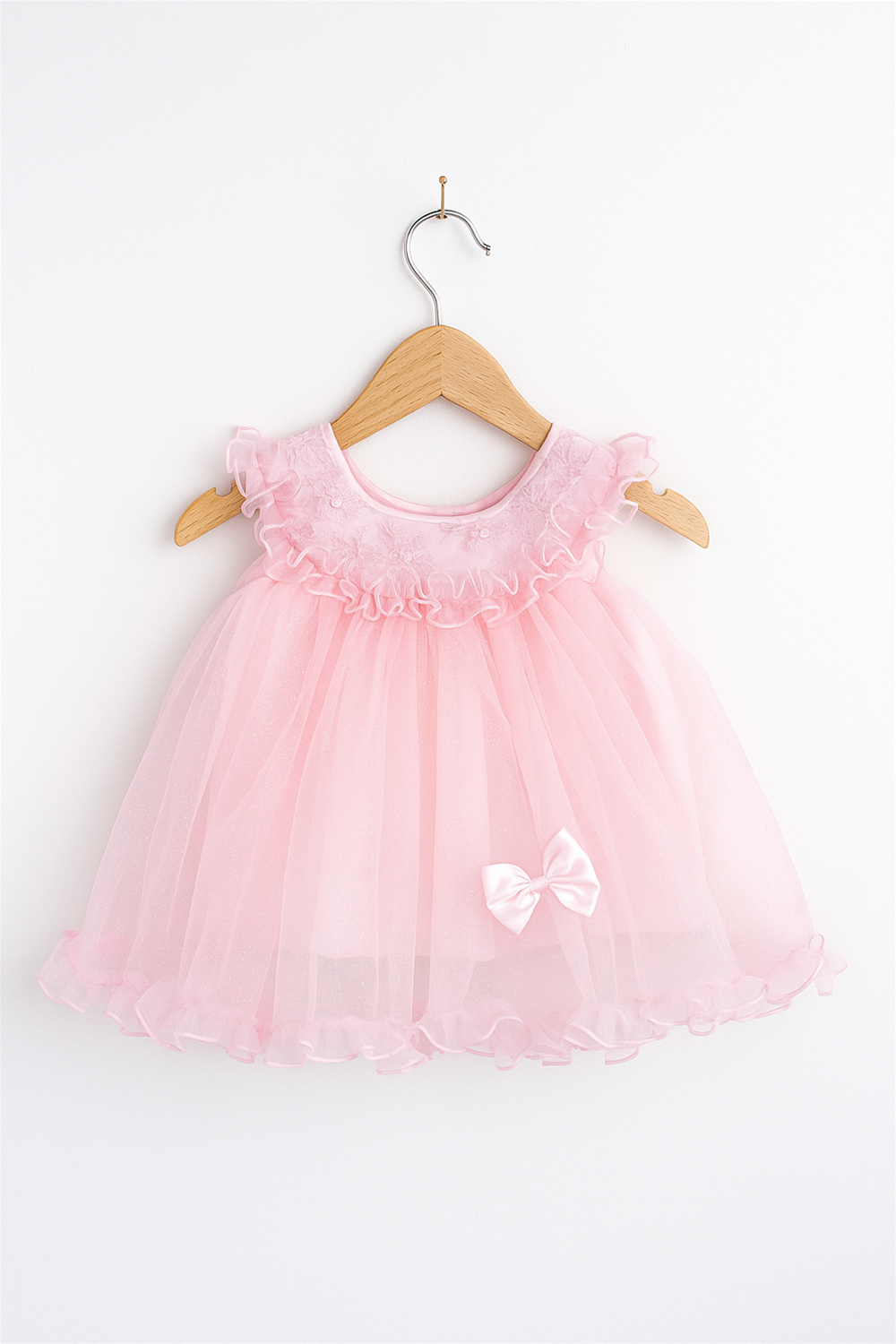 A baby girl's pink dress with a round neck, net skirt, and a bow on the shoulder.