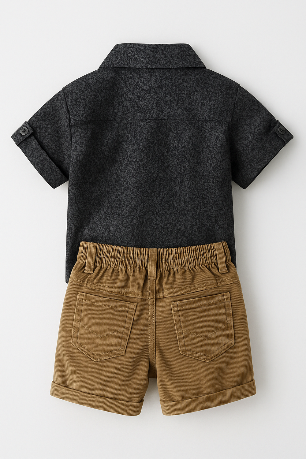 Flat lay of toddler outfit featuring short-sleeve charcoal printed shirt with buttons and beige corduroy shorts, displayed on white background.