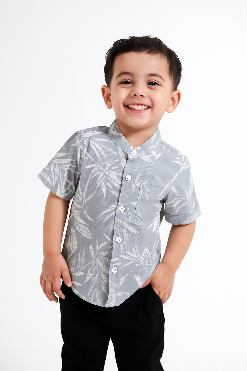 A young boy wearing a stylish half-sleeve Chinese collar shirt with a soft leaf print pattern. The shirt features a front pocket and button closure, perfect for a smart and comfortable summer look.