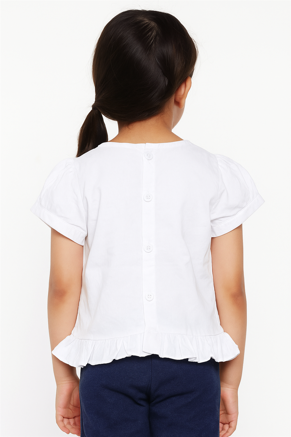 Little girl wearing white ruffle top with buttoned back, paired with blue jeans, showing stylish and simple casual design.