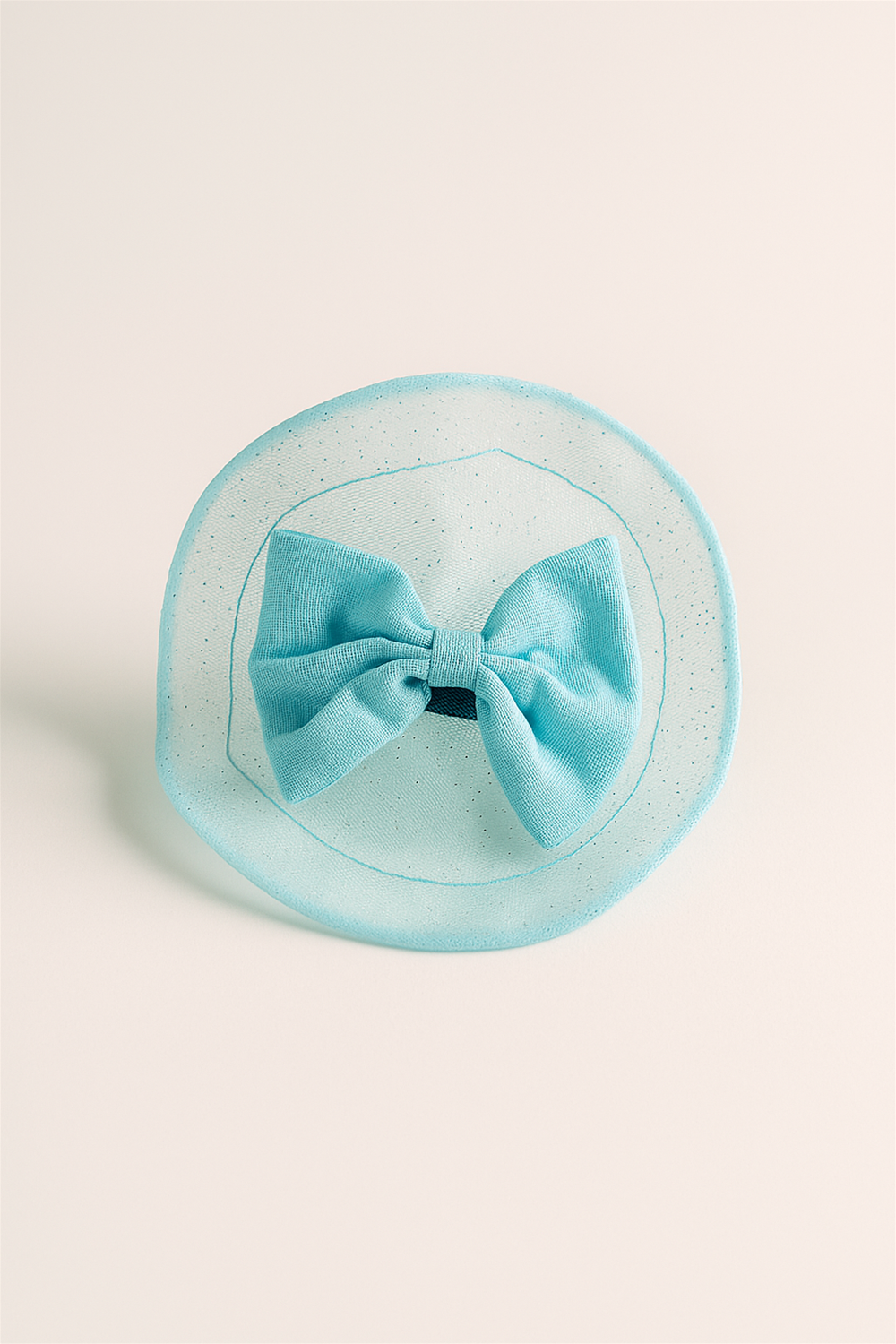 Light blue fabric bow hair clip with glitter-trimmed circular net, photographed against a soft neutral background for product detail.