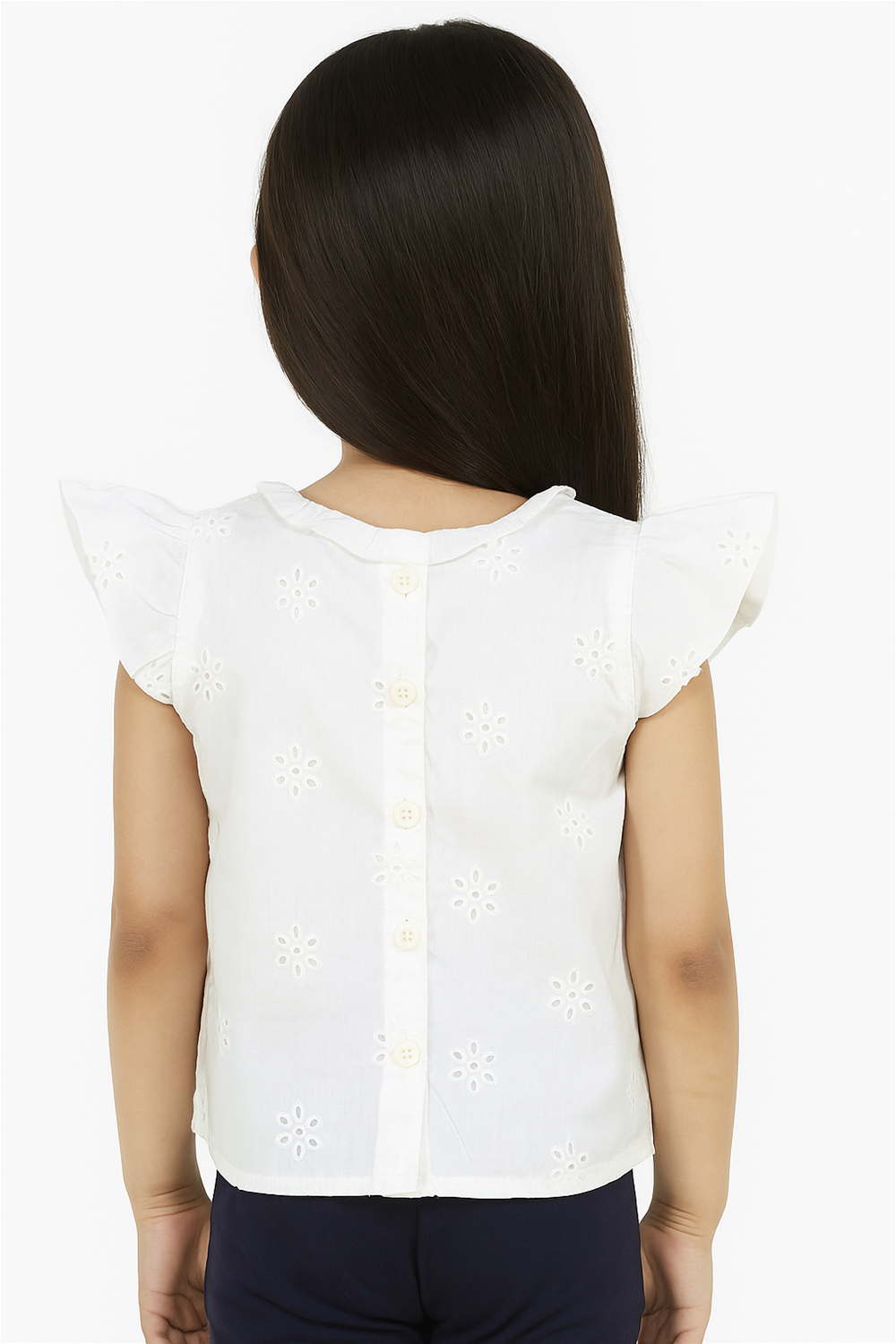 A little girl wears a white embroidered sleeveless top with back button closure and flutter sleeves, showcasing delicate floral patterns.