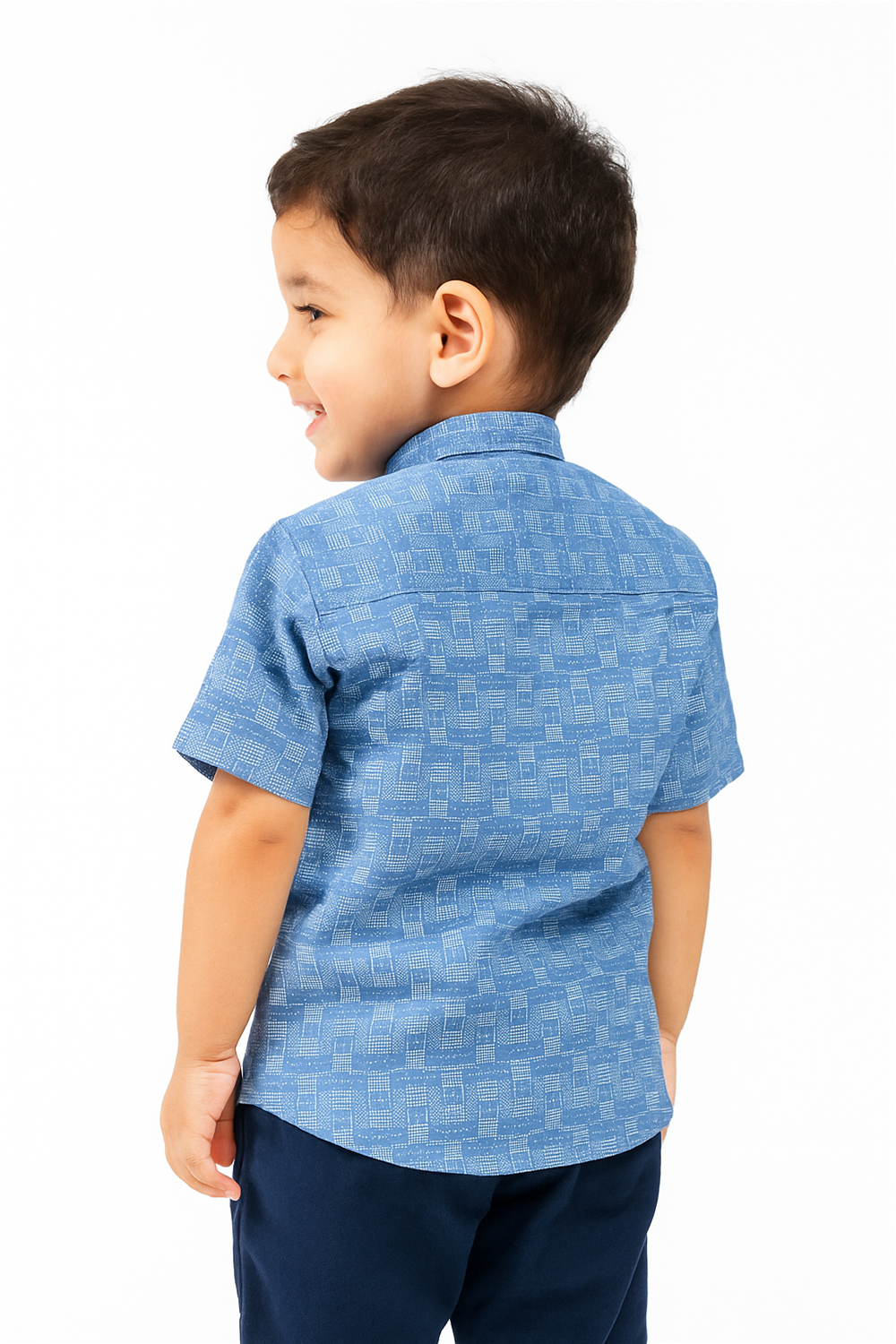 Back view of a young boy wearing a light blue half-sleeve shirt with a Chinese collar and geometric grid pattern. The shirt is neatly tailored with a yoke detail, paired with navy blue trousers, in a bright studio setting.