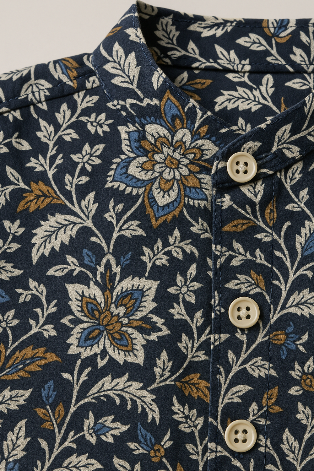 Close-up of navy floral kurta fabric with intricate white, blue, and mustard flower patterns, showcasing fine detailing and button design.
