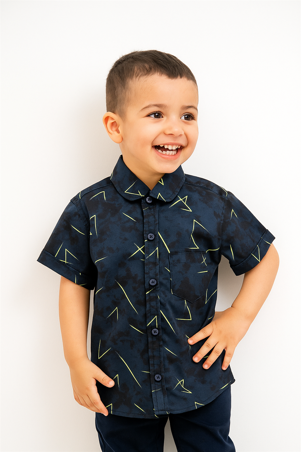 A cheerful young boy wearing a navy blue half-sleeve club collar shirt with yellow geometric prints. The shirt features a front pocket and contrast buttons, adding a fun and trendy touch to kidswear.