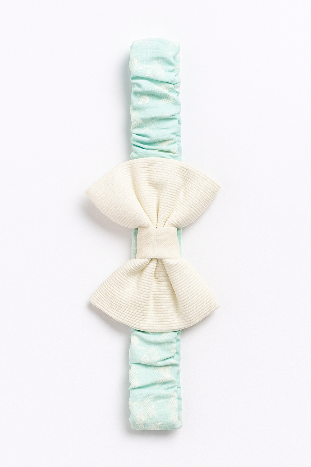 Full view of mint-green elastic hairband with large cream bow centerpiece, styled on a white background for product display.