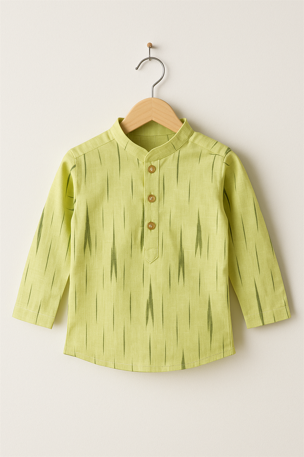 A lime-yellow ikat print kurta with wooden buttons displayed on a wooden hanger against a plain white background, highlighting festive attire.
