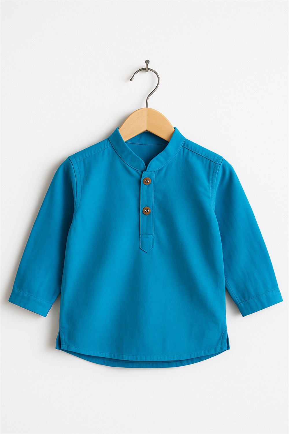 A bright blue boy’s kurta with a Chinese collar and two wooden buttons is displayed on a wooden hanger. The kurta has long sleeves and a plain design, set against a simple white background.