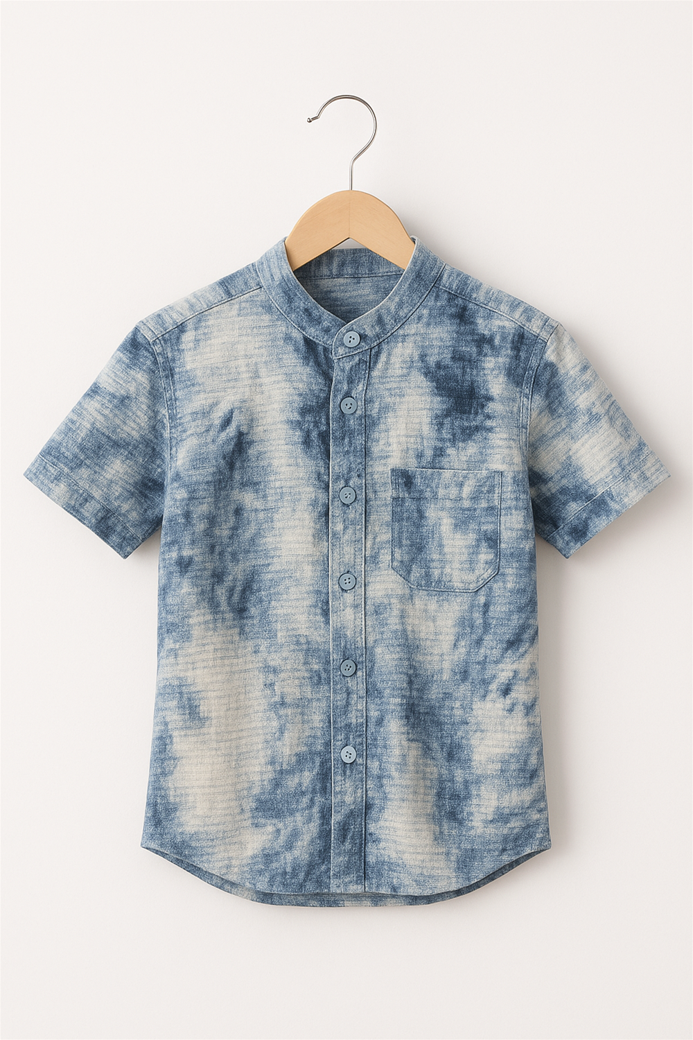 A boy's tie-dye type of design shirt with a Chinese collar and half sleeves hanging on a hanger.