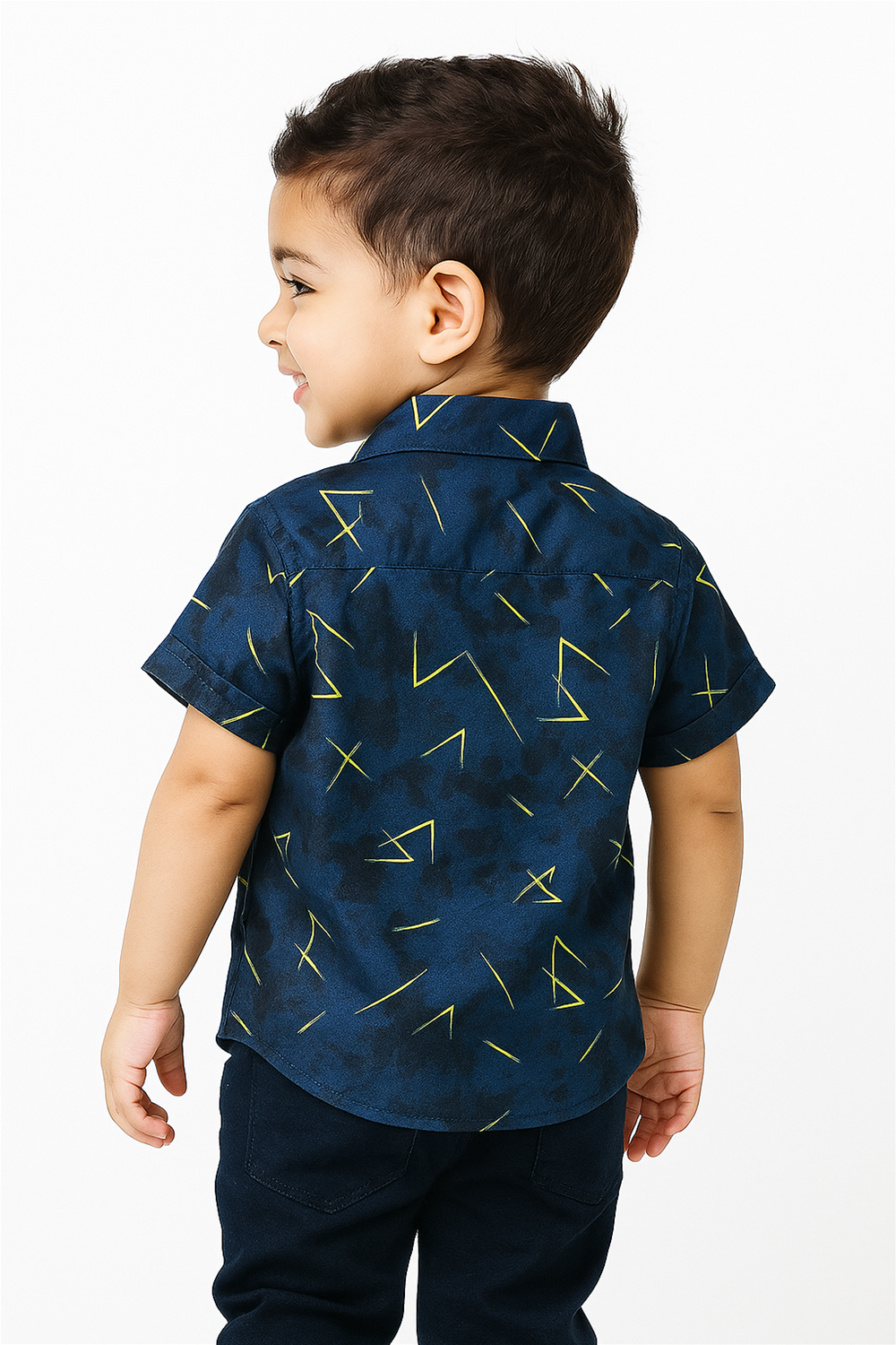 A young boy is seen from the back wearing a navy blue half-sleeve club collar shirt with playful yellow geometric patterns. The shirt offers a modern and stylish look, perfect for casual outings and playful settings.