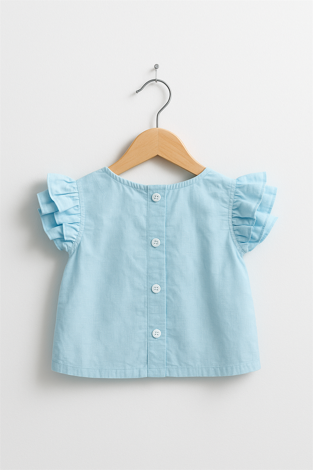 Light blue ruffle-sleeve baby top displayed on wooden hanger, featuring back button closure, neat tailoring, and soft cotton fabric.