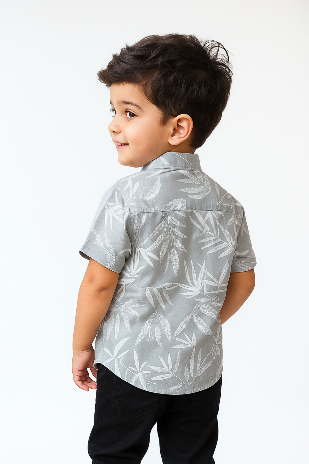 Back view of a boys’ half-sleeve shirt with a Chinese collar, worn by a smiling child. The light grey shirt features a soft leaf print and a structured yoke, offering a relaxed and stylish look.