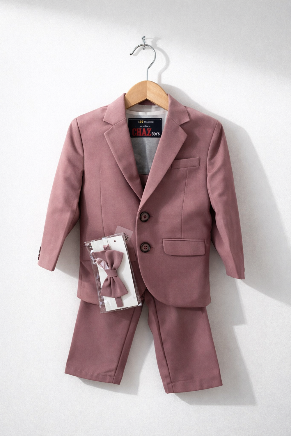 toddler boy suit displayed on wooden hanger, featuring blazer, trousers, and matching bow tie against clean white background.