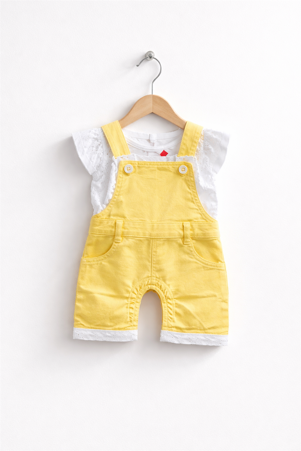 Yellow baby dungaree with white inner top, lace-trim hem, neatly displayed on wooden hanger