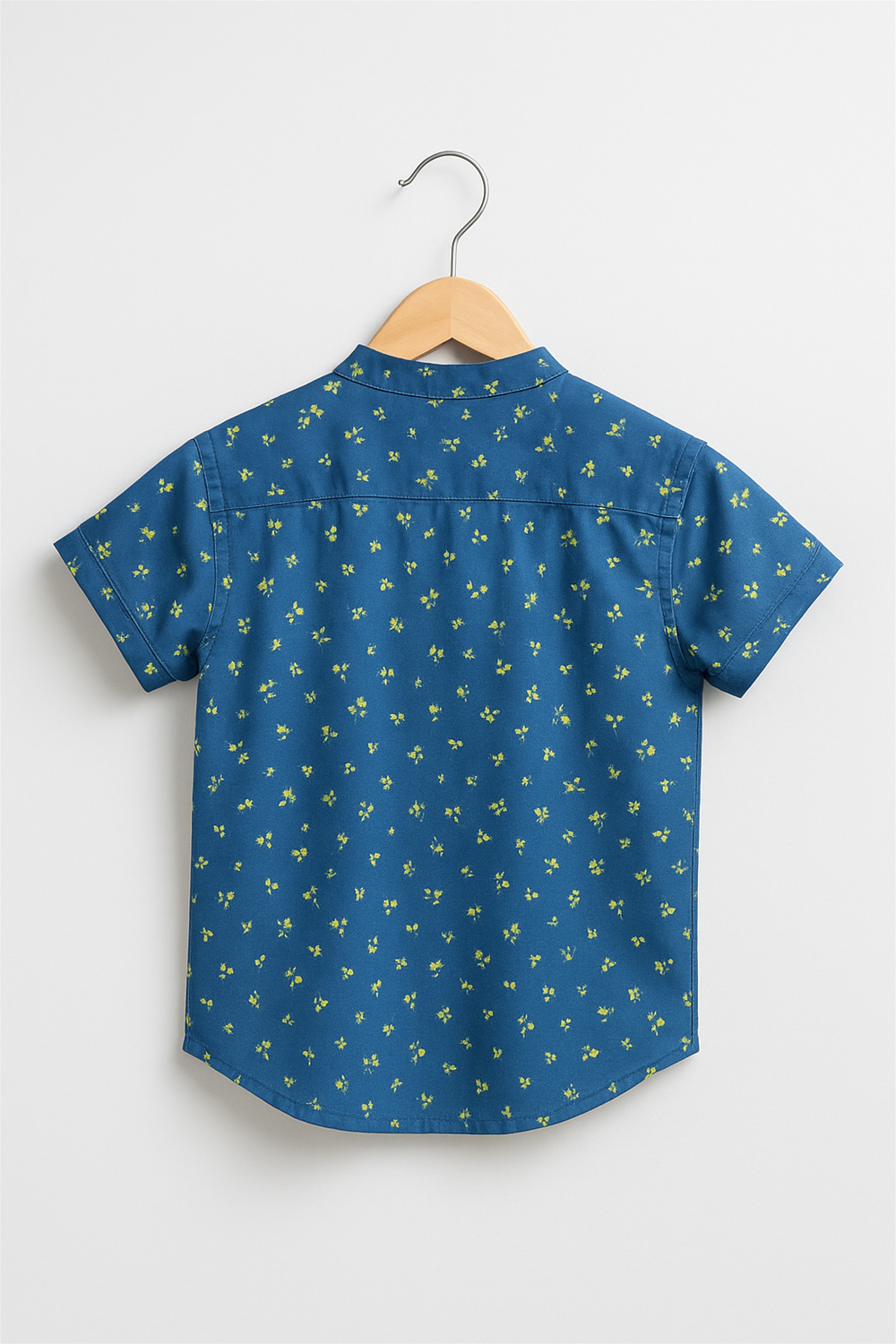 Back view of a boy's half-sleeve Chinese collar shirt in navy blue with a charming green floral print. The shirt is displayed on a wooden hanger against a white background, highlighting its yoke detail and clean stitching.