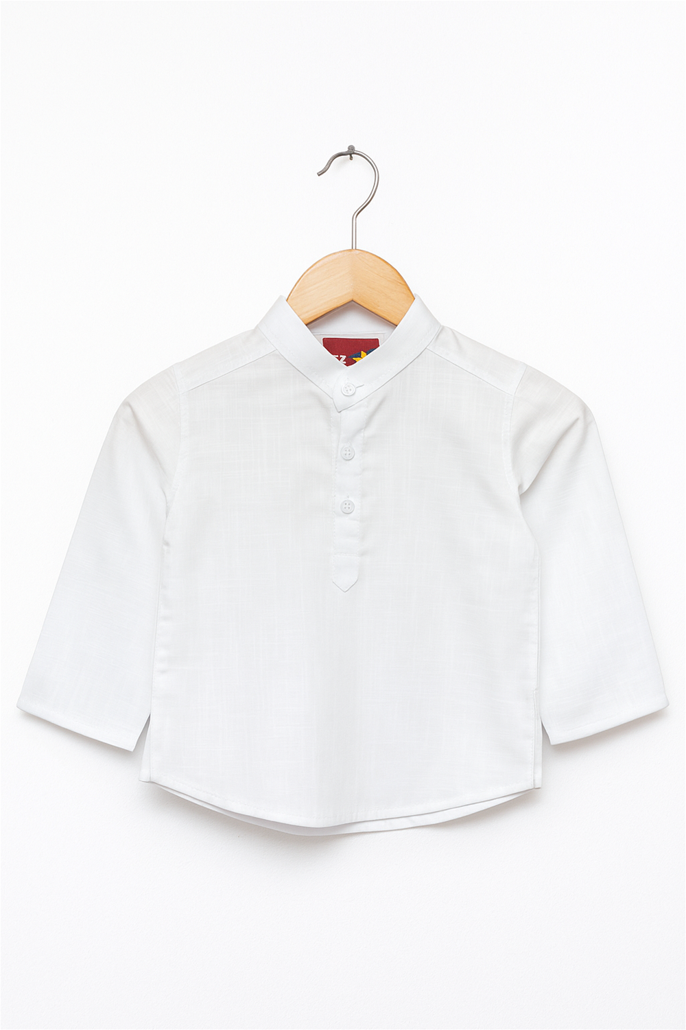 Alternative text: A neatly pressed white cotton boy’s kurta with a Mandarin collar and three-button placket, displayed on a wooden hanger. The kurta has long sleeves and a clean, minimal design, set against a plain white background.