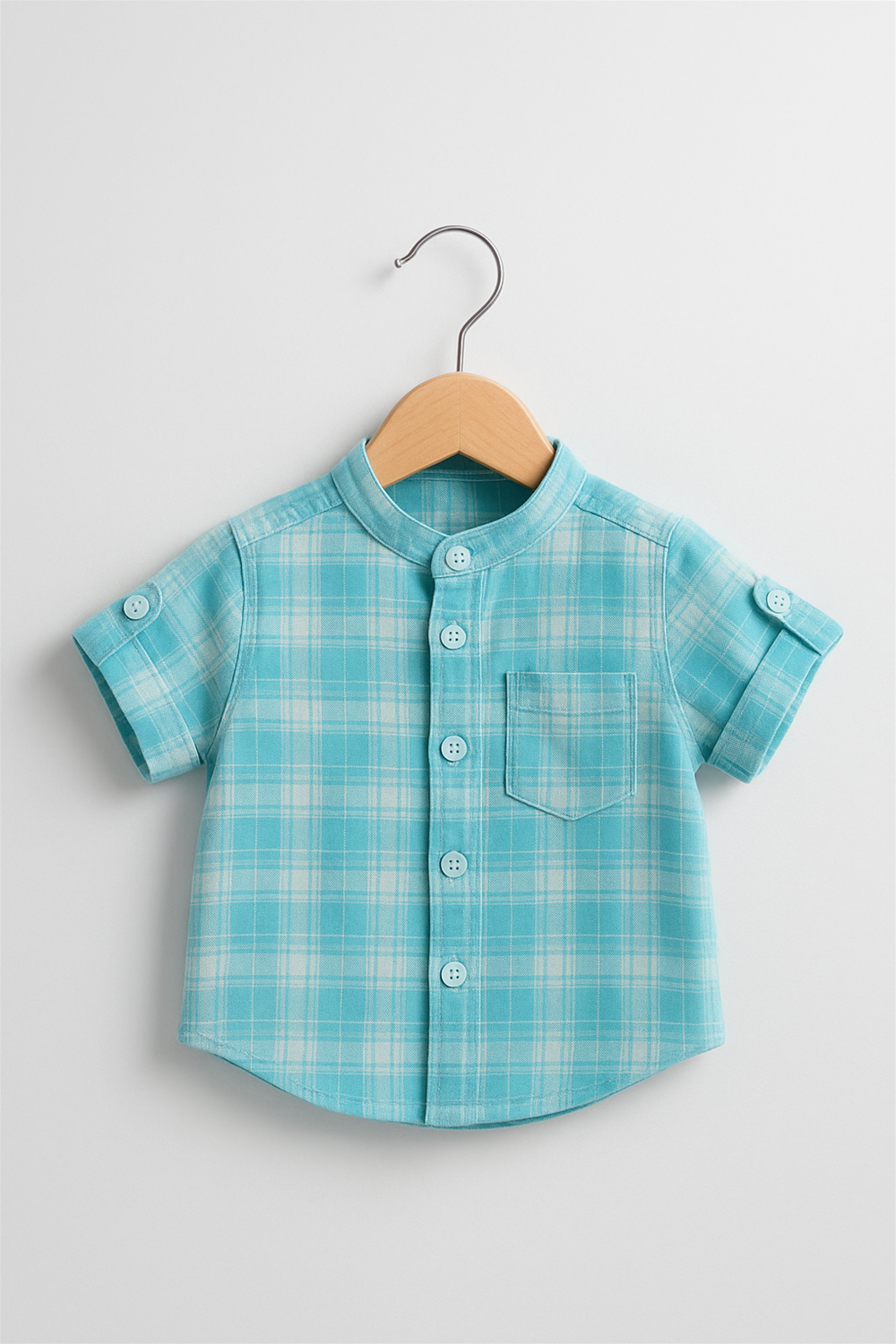Front view aqua plaid short-sleeve baby shirt with buttons and pocket, neatly hung on wooden hanger, white background.