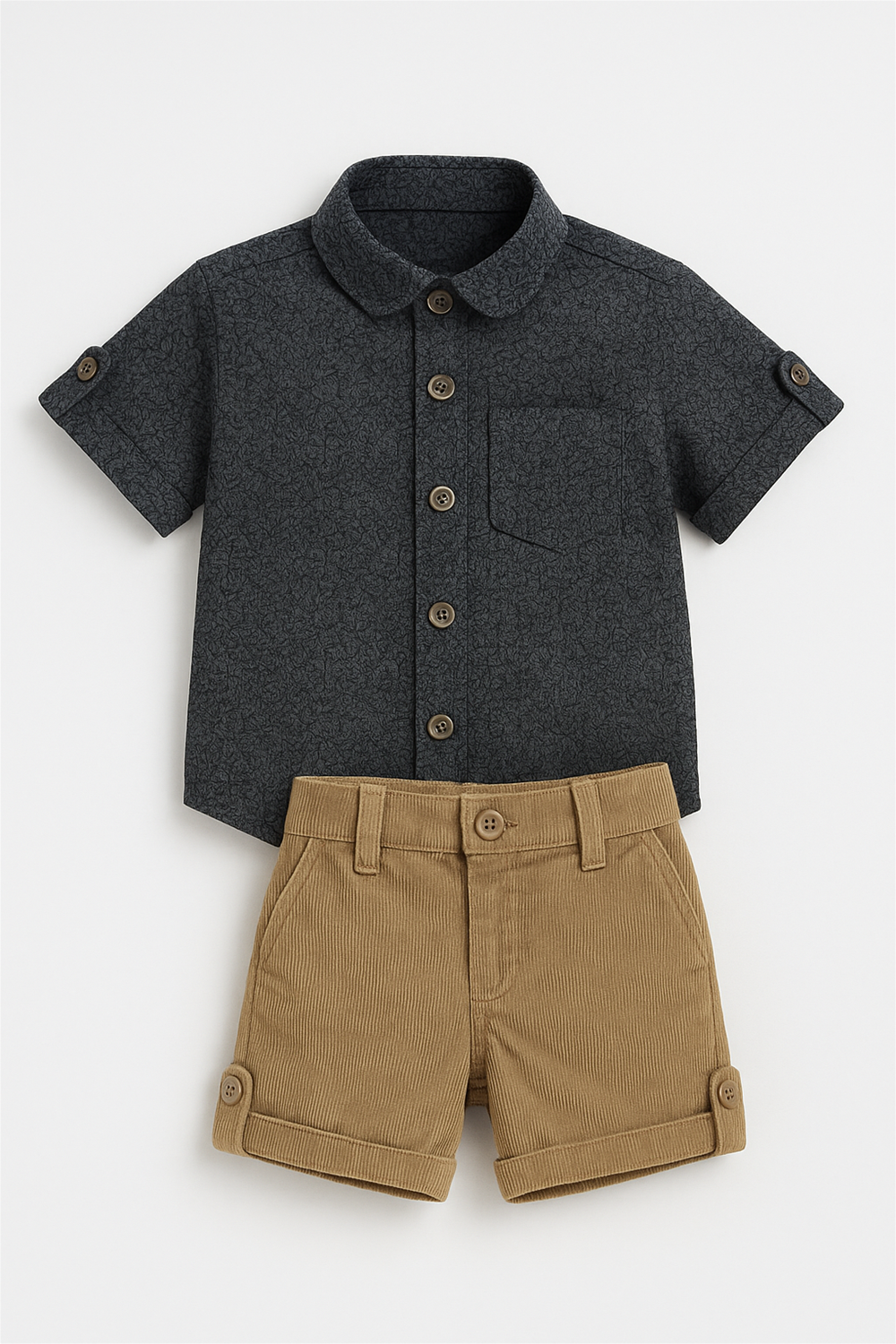 Back view product display of toddler outfit: dark patterned shirt with buttoned sleeves paired with beige corduroy shorts, elastic waistband.
