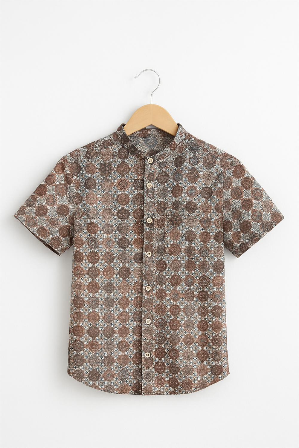 Front vieBack view of a boys’ half-sleeve Chinese collar shirt displayed on a wooden hanger against a white background. The shirt features a rich geometric floral print in earthy tones with a straight yoke and neatly stitched hem.w of a boys’ half-sleeve Chinese collar shirt hanging on a wooden hanger against a white background. The shirt features an intricate all-over geometric print in earthy tones with a button-down front and clean tailoring.
