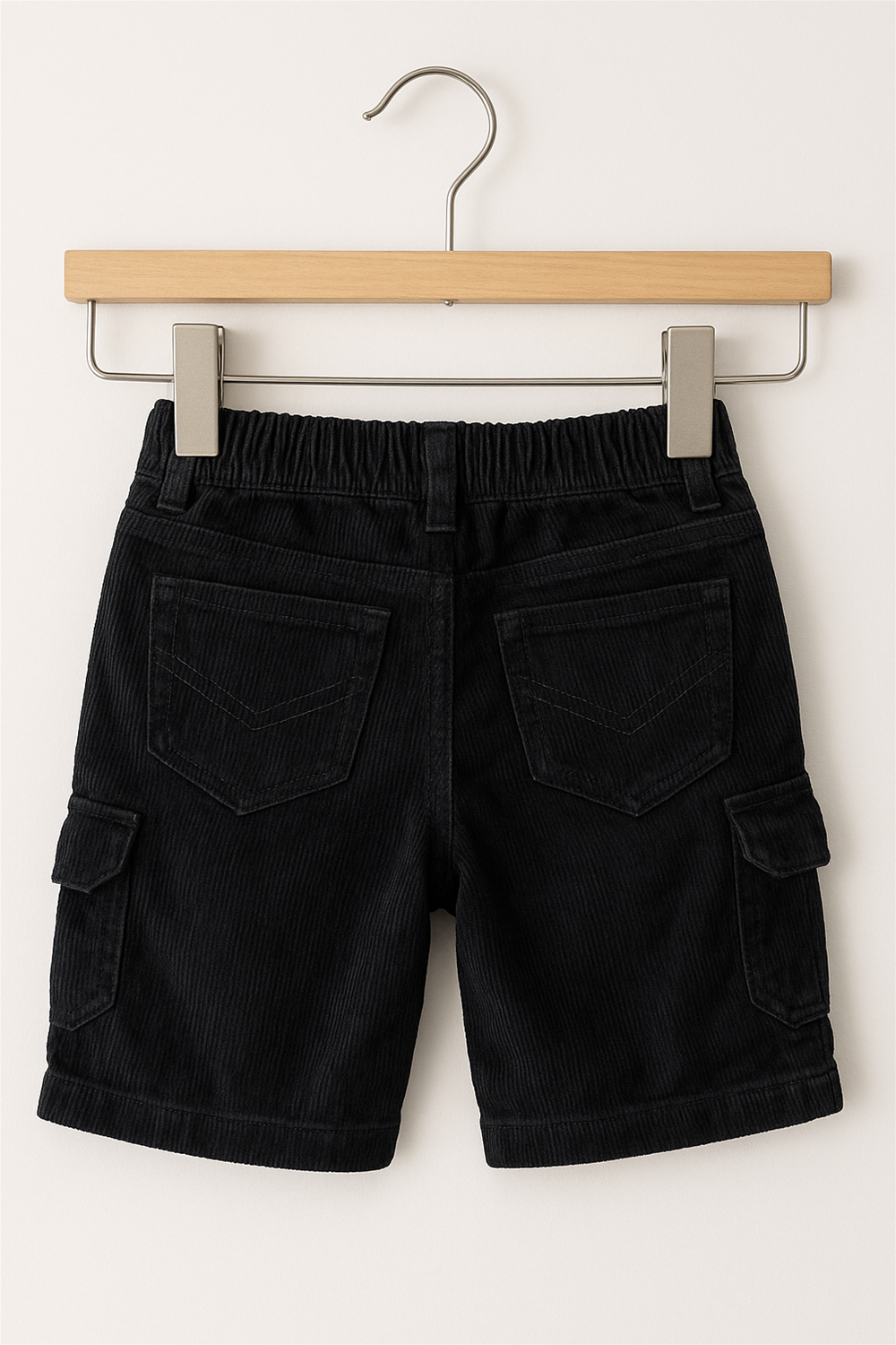 Black half pants with box side pockets and buttons. In Wooden Hanger Back View. 
