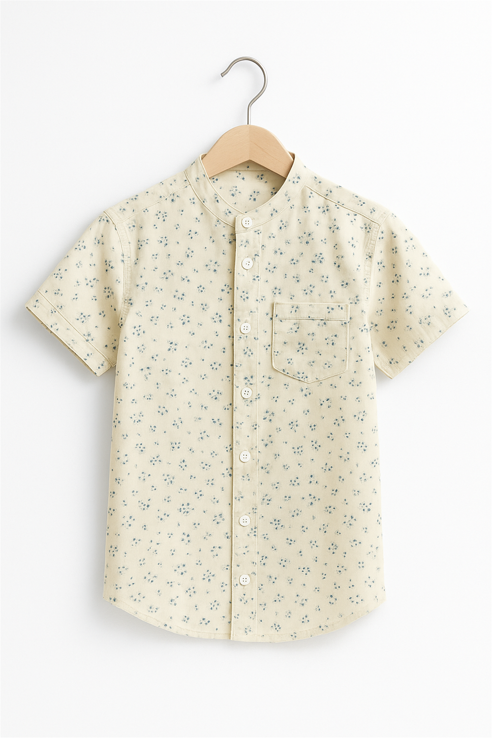Front view of a boy’s half-sleeve Chinese collar shirt in light yellow, neatly displayed on a wooden hanger. Features subtle blue floral prints and a chest pocket, ideal for casual and semi-formal occasions.