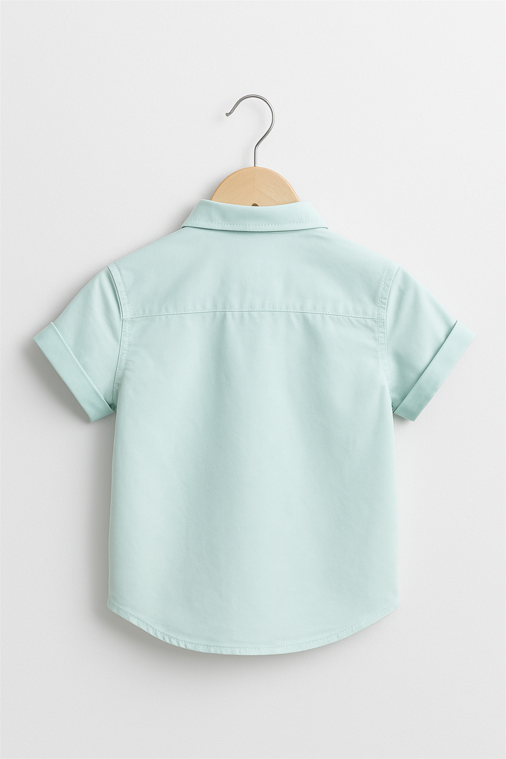 Back view of a mint green half sleeves boys' shirt with a Chinese collar, displayed on a wooden hanger. Features clean stitching, rolled sleeves, and a soft pastel tone perfect for summer wear.