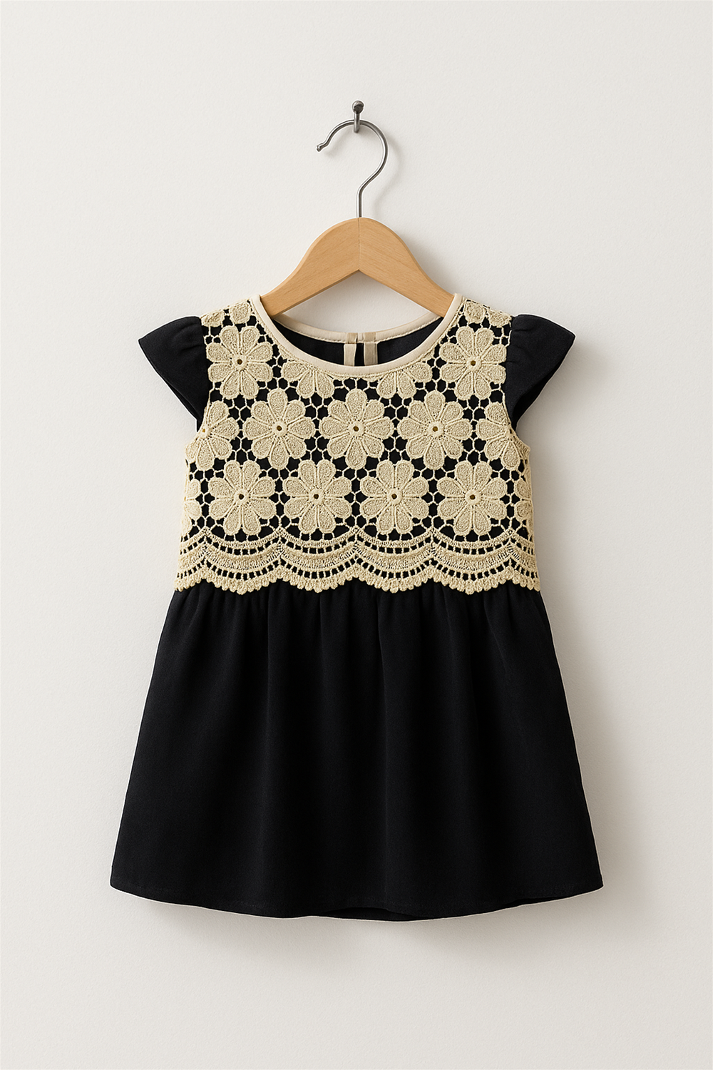 A off white cut work with black velvet party wear frock in a wooden hanger front view.