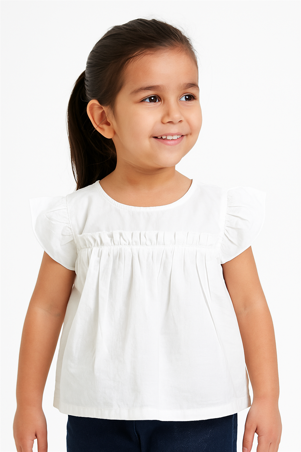 Smiling girl wearing a white flutter-sleeve pleated top, styled simply with navy blue pants, perfect for summer occasions.