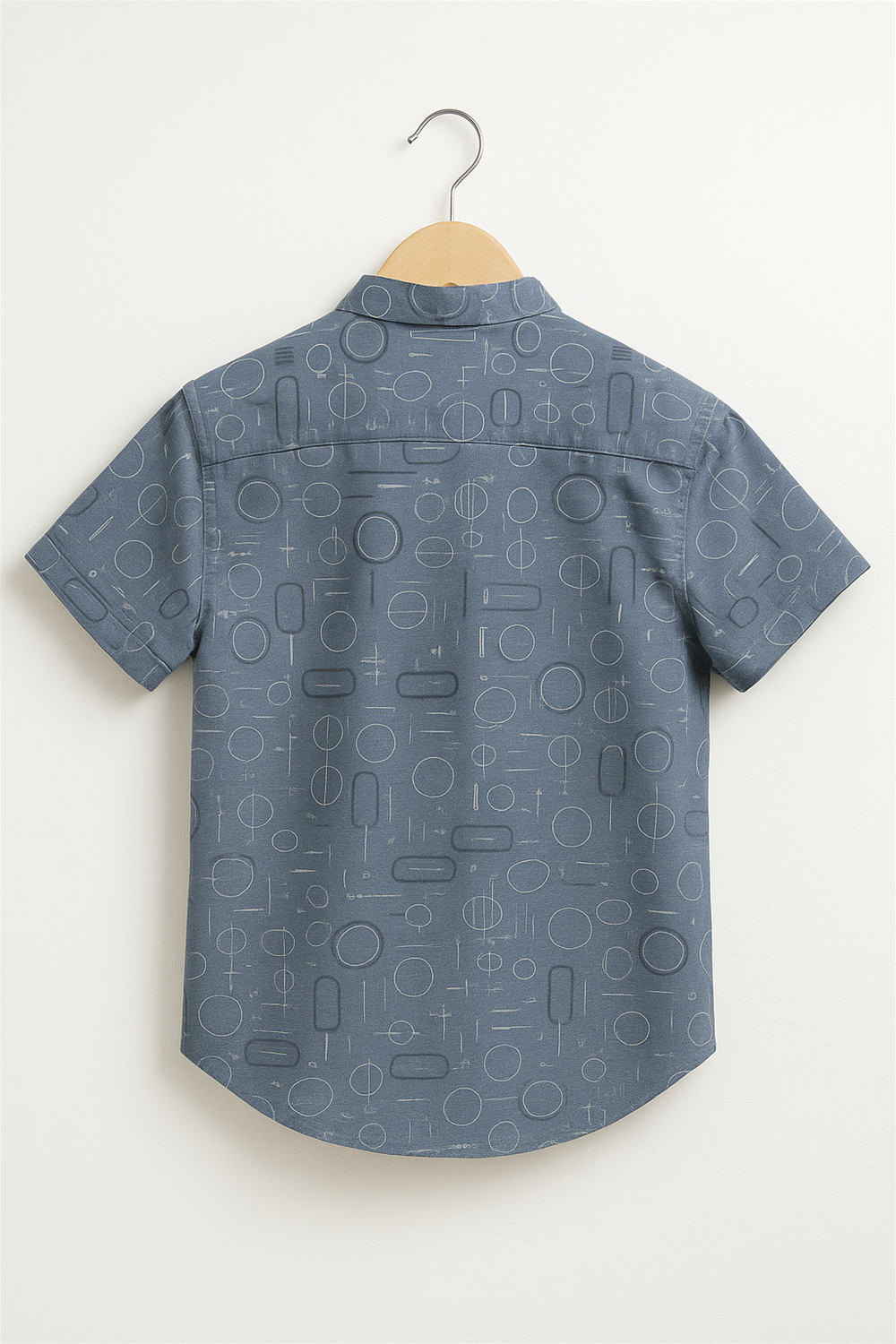Back view of a boys' half-sleeve club collar shirt displayed on a wooden hanger. The shirt features a playful geometric print in white, ideal for casual summer wear.