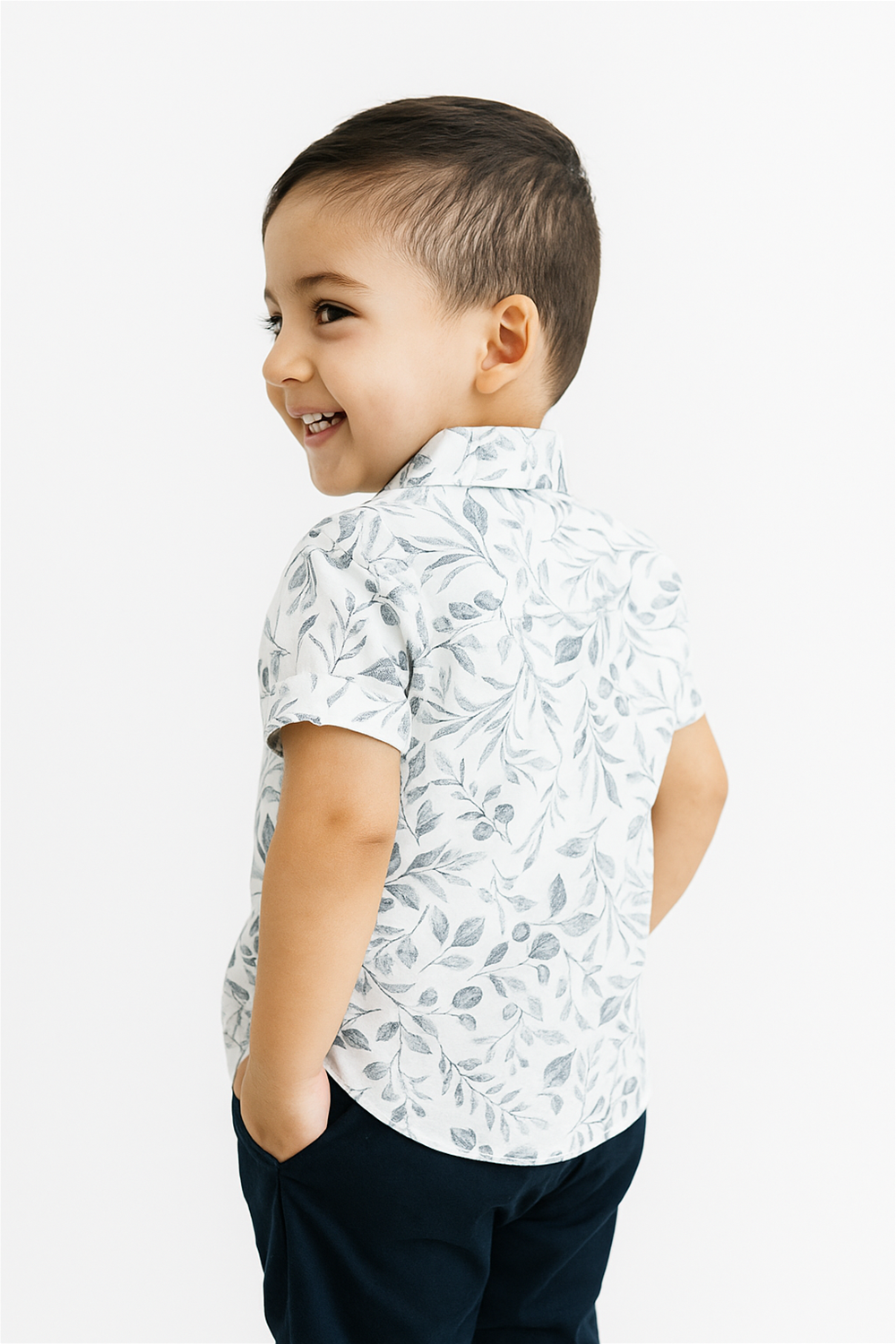Back view of a boy wearing a half-sleeve club collar shirt with a soft leaf print on a cream base. The shirt showcases a clean, structured fit with a playful and comfortable look perfect for casual outings.