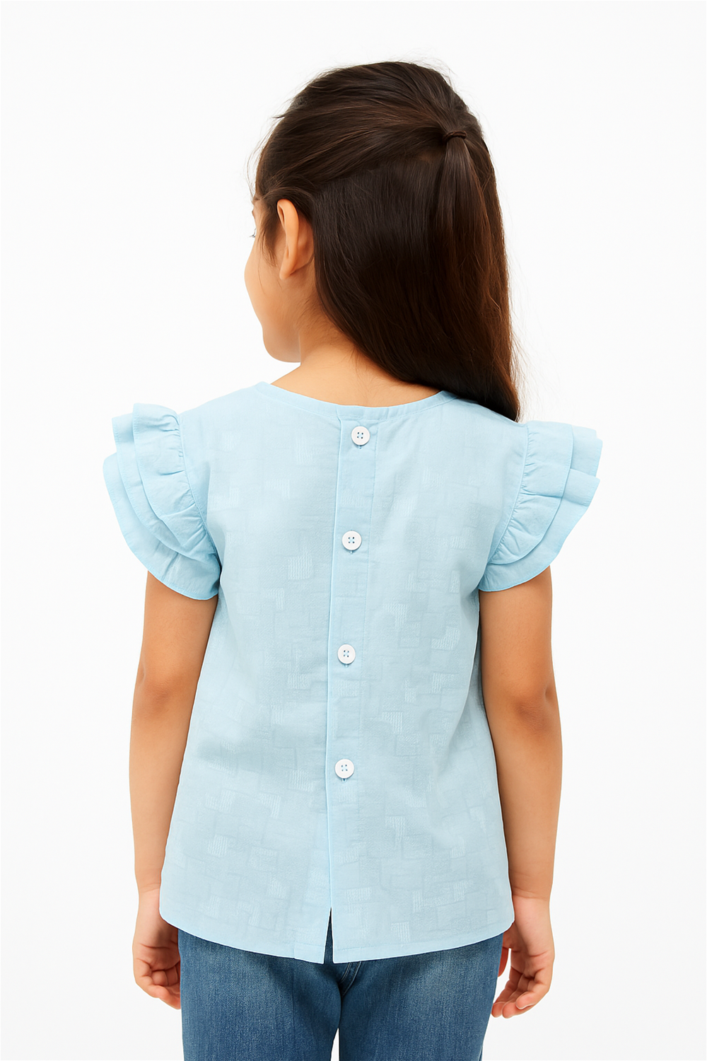 Girl wearing light blue ruffled top with back buttons, showing rear view, styled with jeans, natural pose, minimal background.