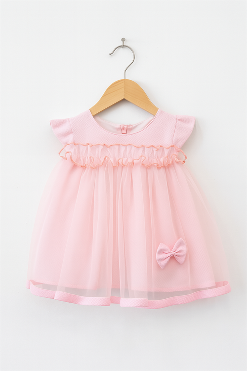 A soft pink toddler dress with a ruffled bodice, sheer overlay, and a cute bow accent, displayed on a wooden hanger against a white background.