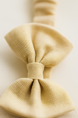 A close-up shot of the beige fabric hair band bow, highlighting its woven grid-like texture. The fine details of the material give a soft, handcrafted appeal.