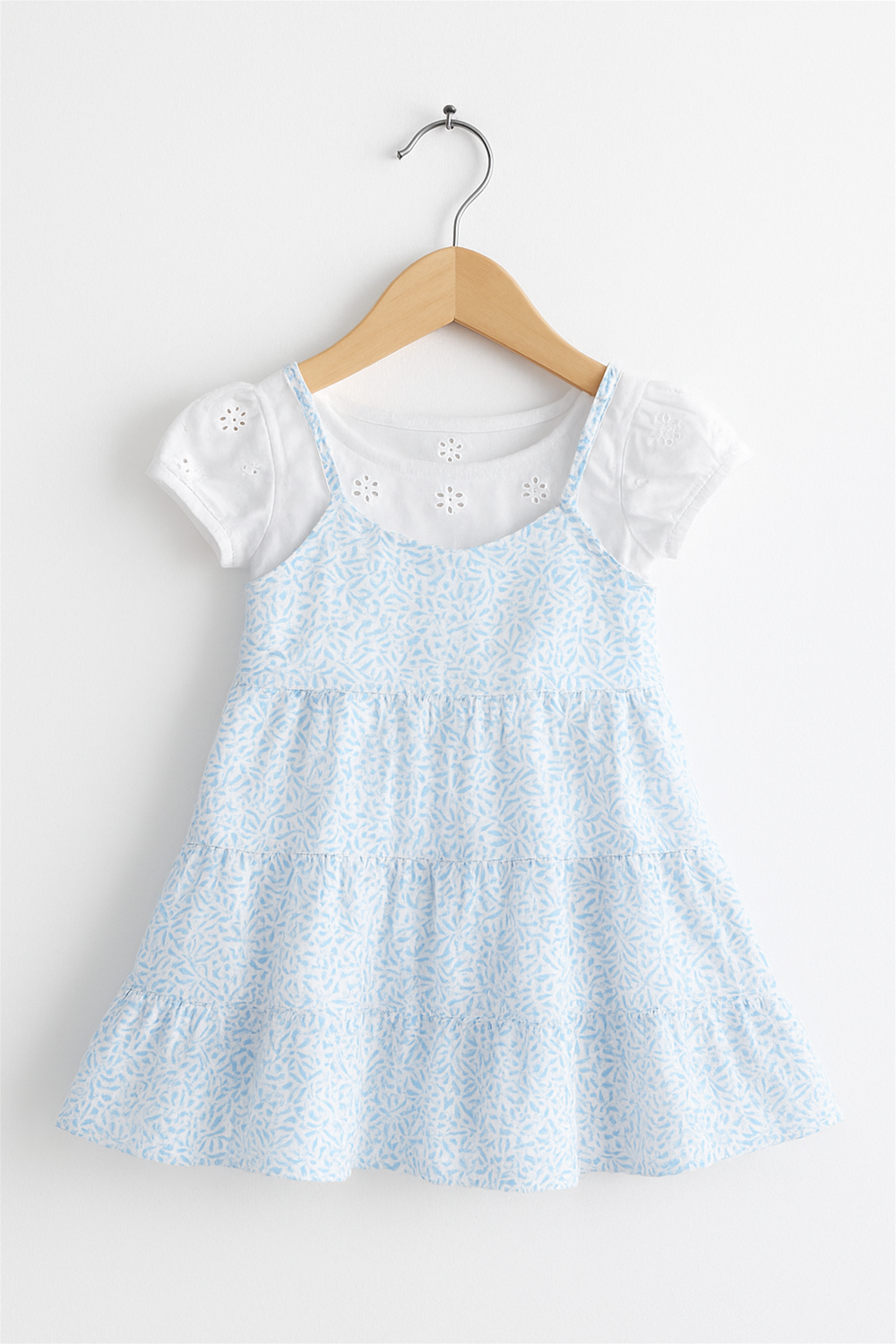 A sky-blue tiered frock features delicate floral patterns and puff sleeves in hanger front view.