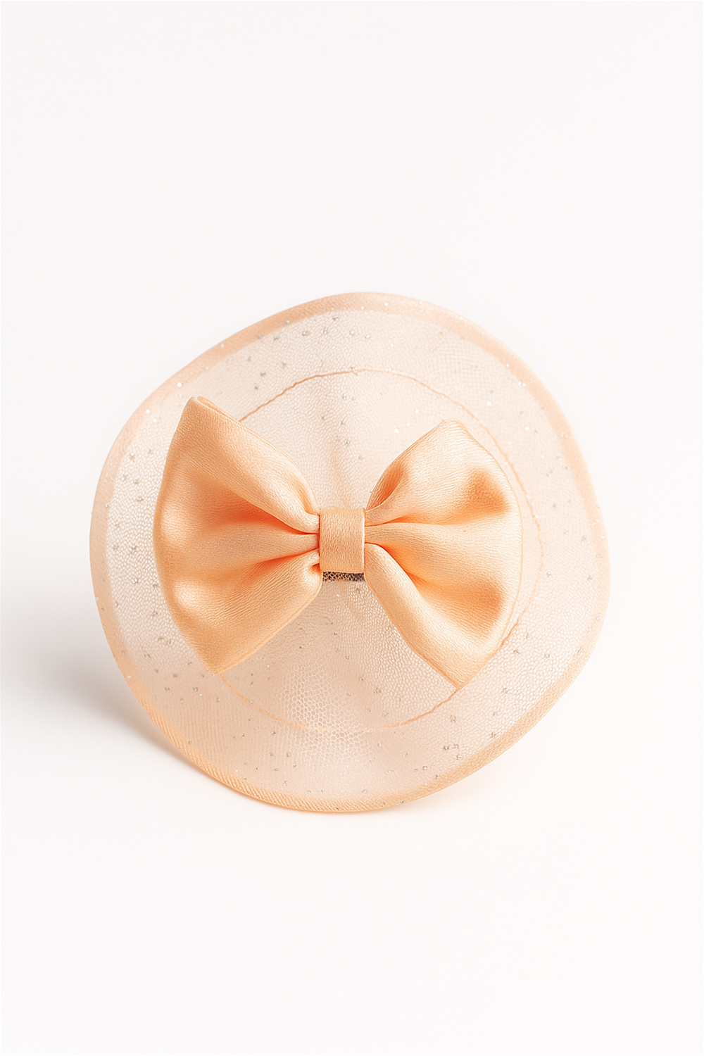 Peach bow hair clip with glittery circular netted base, placed against white background, highlighting its delicate and stylish design