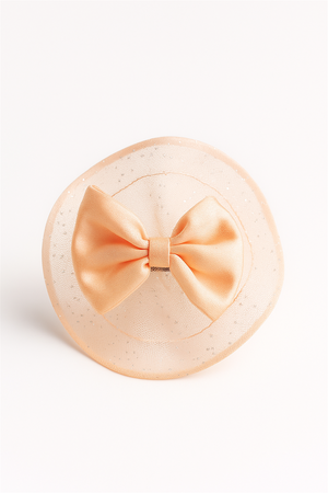 Peach bow hair clip with glittery circular netted base, placed against white background, highlighting its delicate and stylish design